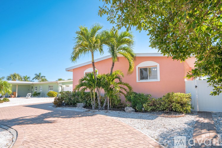 A pink house with a white fence and a gravel driveway.