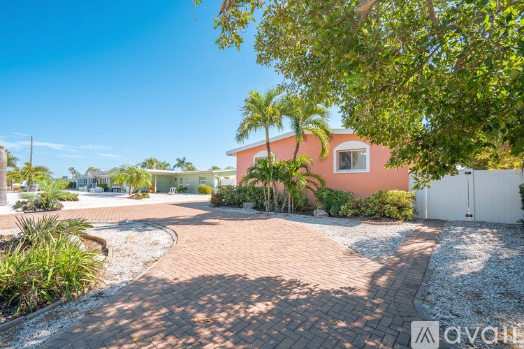 A house with a pink exterior is surrounded by a driveway and landscaping.