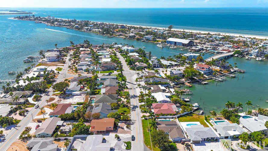 A bird's eye view of a coastal residential area with houses, roads, and boats.
