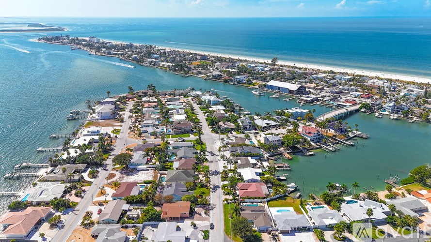 A coastal town with a mix of residential and commercial buildings is shown from an aerial perspective.