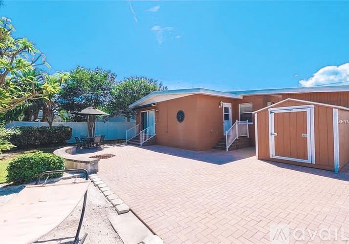 A sunny day at a property with a brown building and a brick patio.