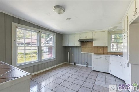 A kitchen with white cabinets and a wooden countertop.