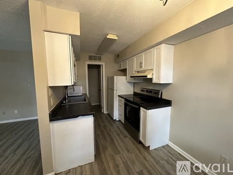 A kitchen with white cabinets and black countertops.