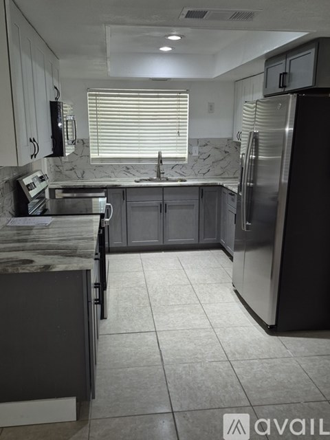 A kitchen with a marble countertop and stainless steel appliances.