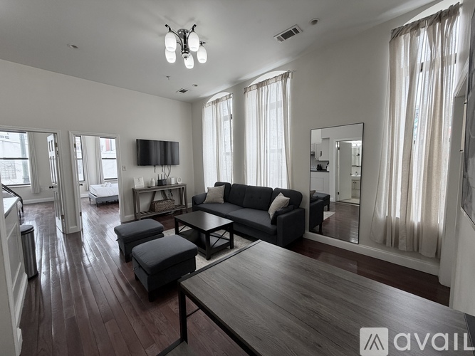 A living room with a grey couch and a kitchen in the background.