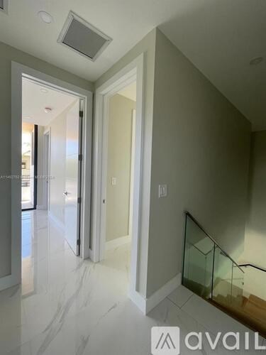 A hallway with a glass railing and a marble floor.