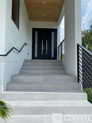 A set of stairs leading to a black door with a glass panel.