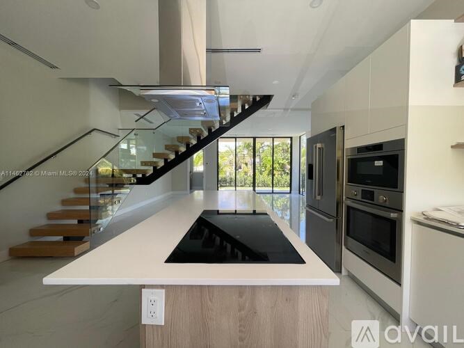 A modern kitchen with a staircase leading to the upper level.