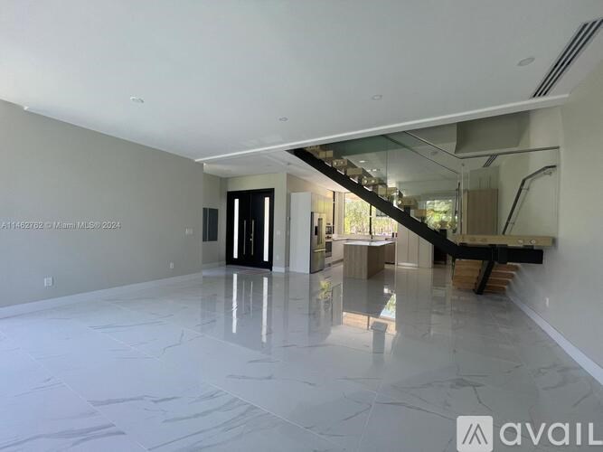 A spacious, empty room with a marble floor and a staircase in the background.