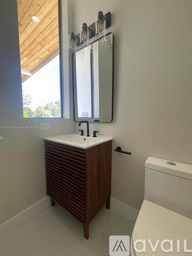 A bathroom with a sink, toilet, and mirror.