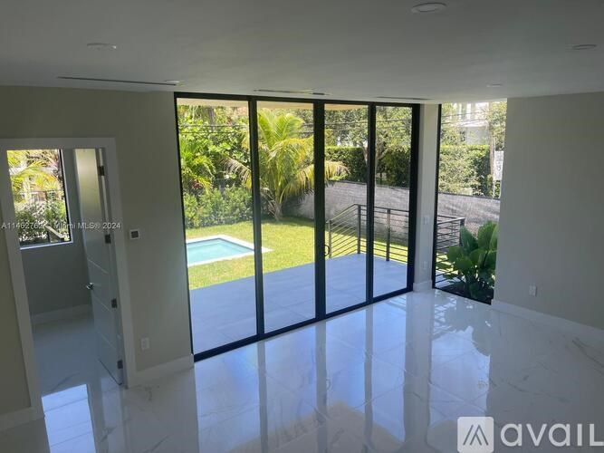 A room with a view of a pool and greenery outside.
