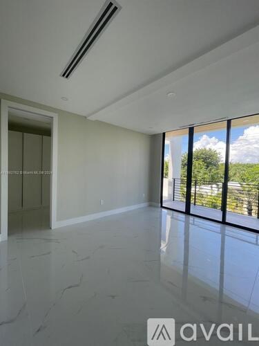 A spacious room with marble flooring and a view of the outdoors through large windows.