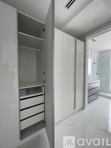 A white bathroom with a walk in shower and a vanity with drawers.