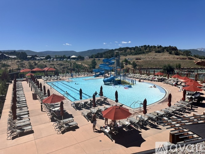 A large outdoor swimming pool surrounded by sun loungers and umbrellas.