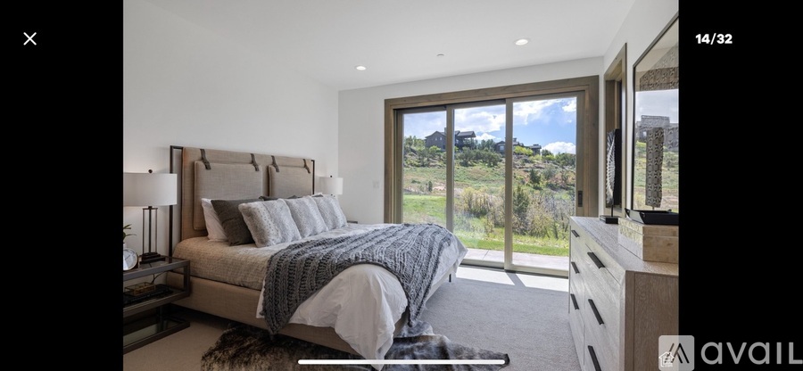 A bedroom with a large bed and a view of the countryside through the window.