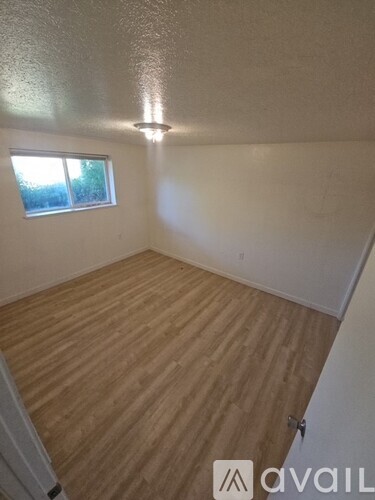 A room with wooden flooring and a window.