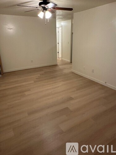 A room with wooden flooring and a ceiling fan.