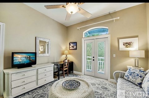 A living room with a television, a chair, a table, and a couch.