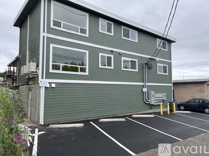A green building with a grey roof and a parking lot in front.
