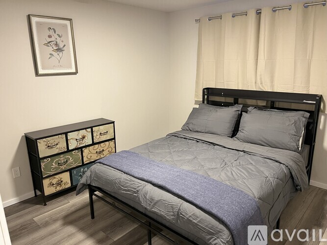 A bedroom with a bed, nightstand, and a picture on the wall.