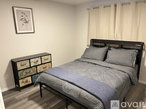 A bedroom with a bed, nightstand, and a picture on the wall.