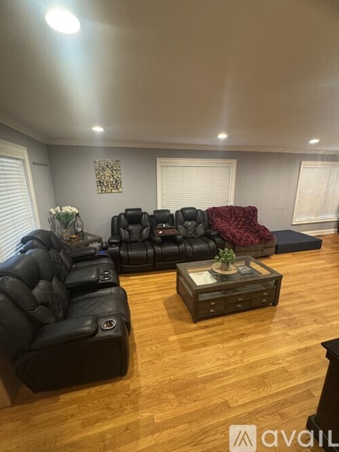A living room with black leather sofas and a wooden coffee table.