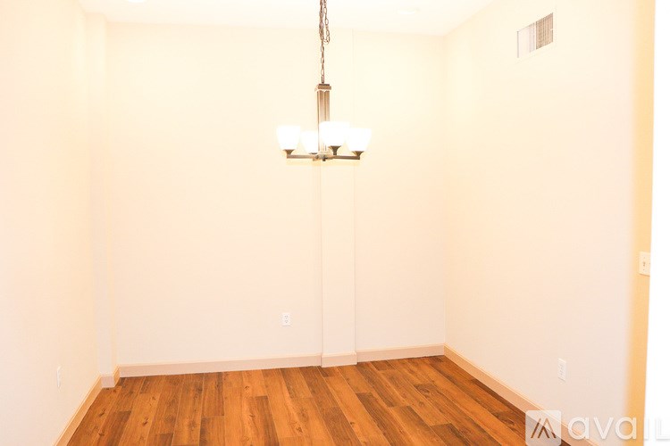 A room with wooden floors and a chandelier hanging from the ceiling.