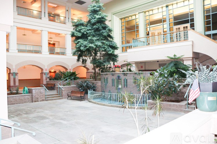 A courtyard with a tree, a bench and a fence.
