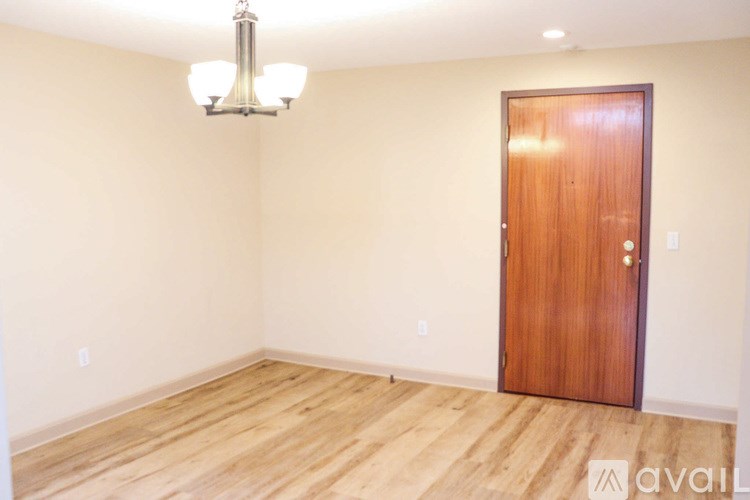 A room with a wooden door and a chandelier hanging from the ceiling.