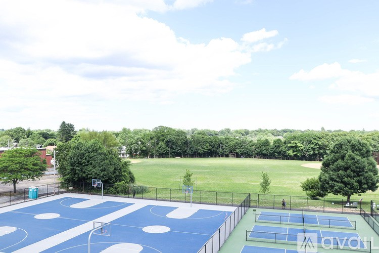 A tennis court with a blue and white color scheme is surrounded by a fence and trees.