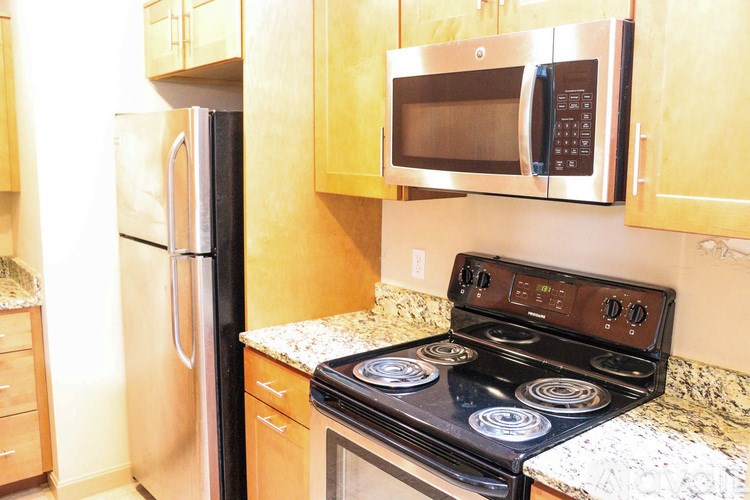 A kitchen with a stove, refrigerator, and microwave.