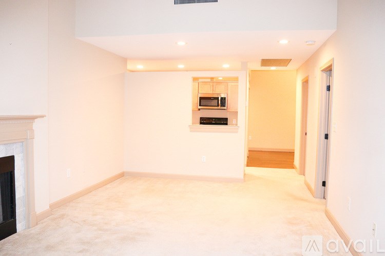 A spacious living room with a fireplace and a kitchen in the background.
