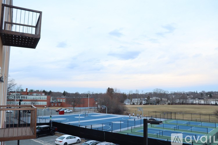 A tennis court is surrounded by a parking lot.