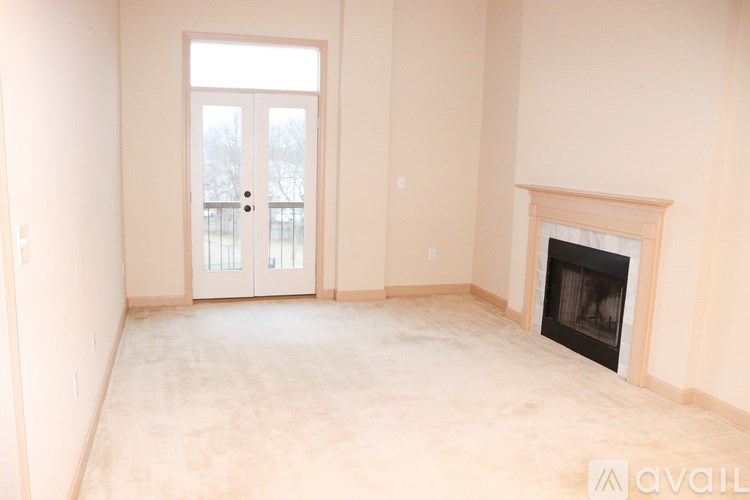 A large empty room with a fireplace and a door leading outside.