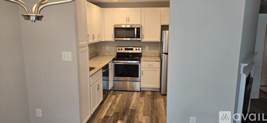 A kitchen with white cabinets and a wooden floor.