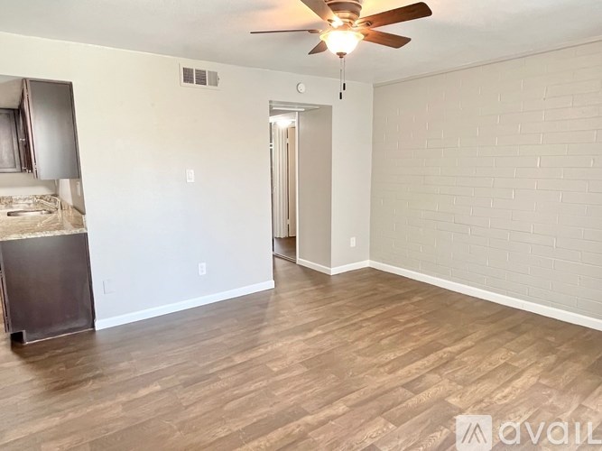 A room with a ceiling fan and wooden flooring.