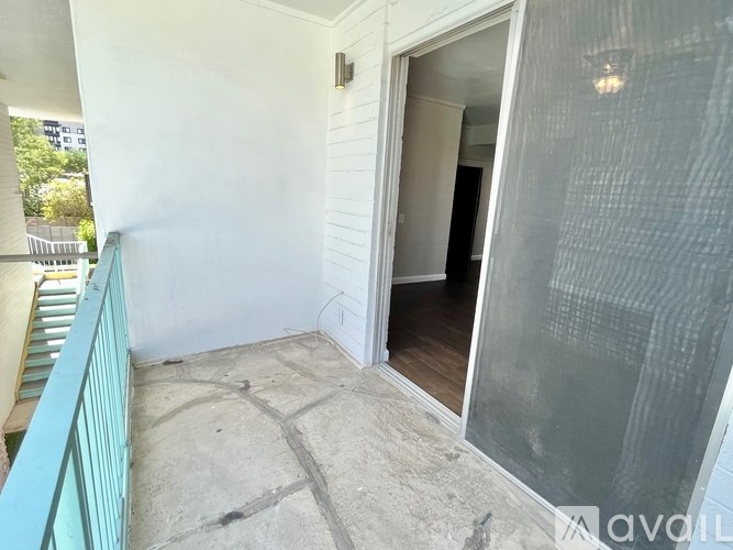 A balcony with a glass door leading to a dark room.