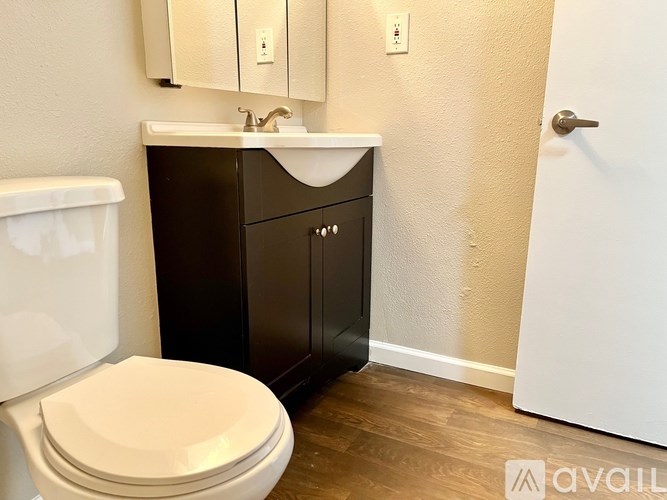 A bathroom with a toilet, sink, and cabinet.