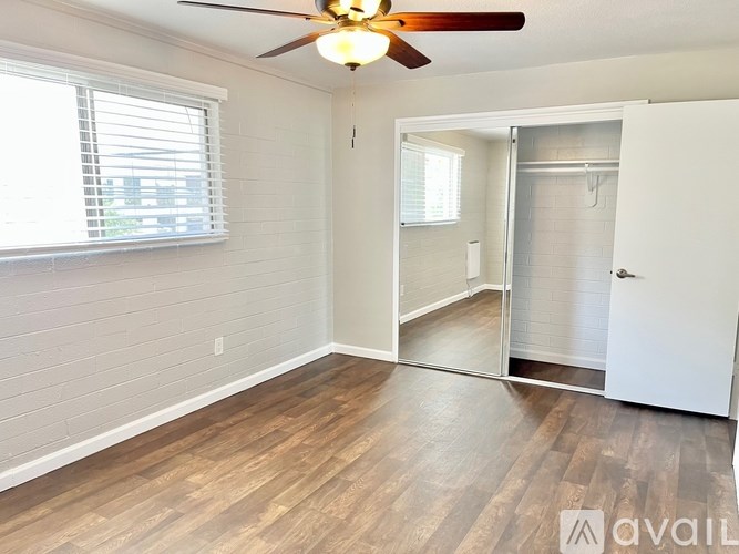 A room with a ceiling fan and wooden flooring.