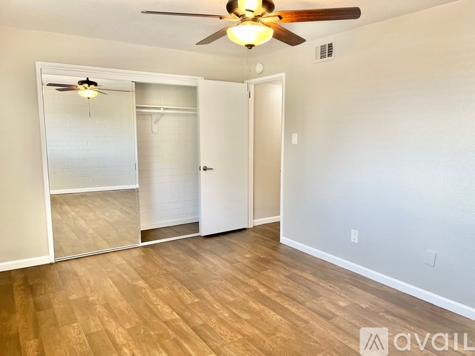 A room with a ceiling fan and wooden flooring.