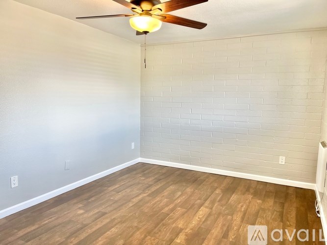 A room with a ceiling fan and wooden flooring.
