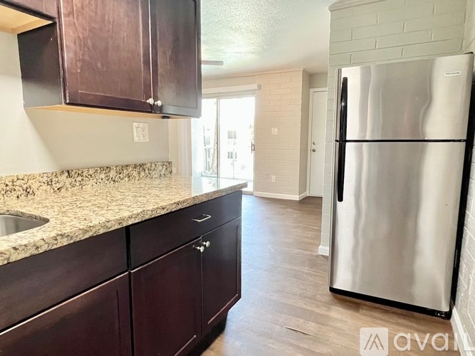 A kitchen with dark wood cabinets and a stainless steel refrigerator.
