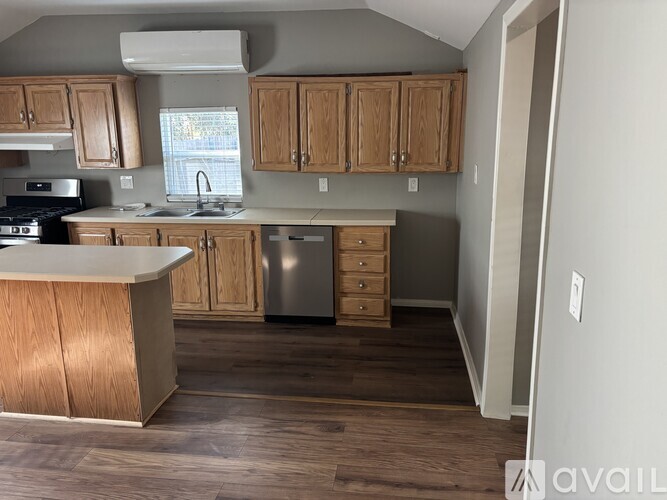 A kitchen with a fan, a window, and a trash bin.