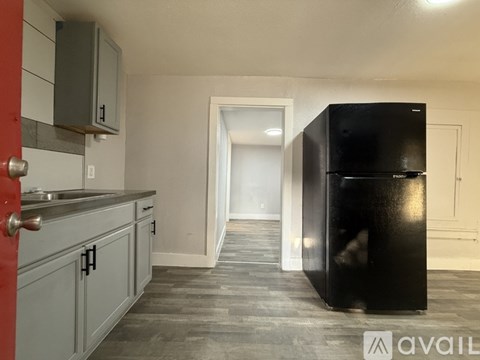 A kitchen with a black fridge and a red door.