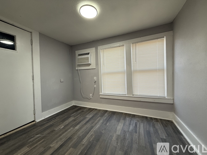 A room with a window, a door, and a wall-mounted air conditioner unit.