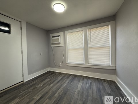A room with a window, a door, and a wall-mounted air conditioner unit.