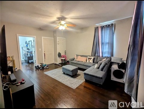 A living room with a grey couch and a ceiling fan.