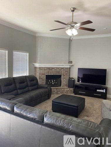 A living room with a black leather couch and a fireplace.