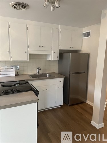 A kitchen with white cabinets and a stainless steel refrigerator.