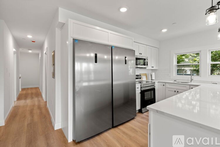 A modern kitchen with a stainless steel refrigerator and wooden flooring.